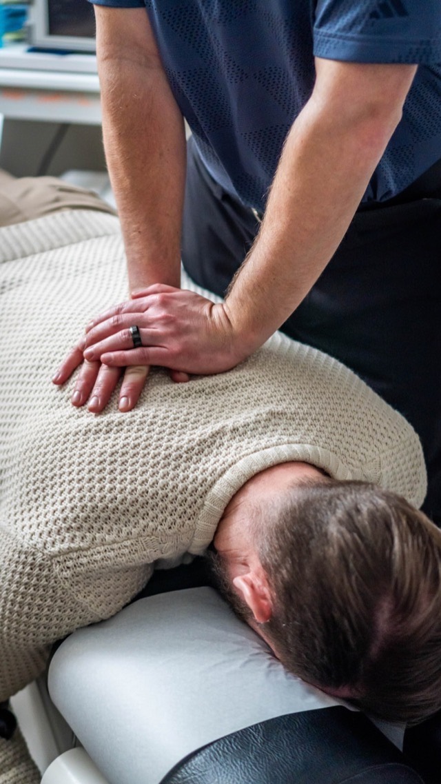 A chiropractor adjusting a patient's upper back